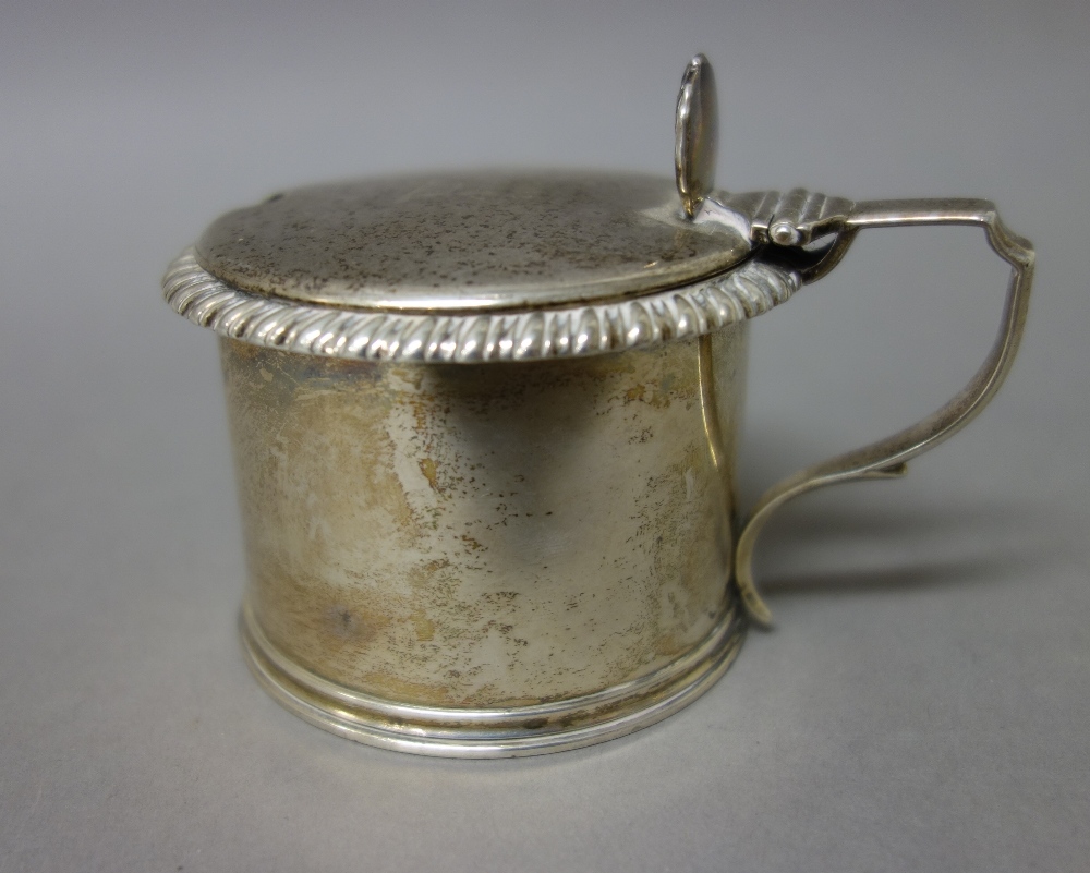 A William IV silver hinge lidded mustard pot of cylindrical form, decorated with a gadrooned rim,