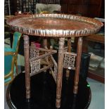 An Eastern embossed copper tray table and stand and a cream printed oval metal tray.