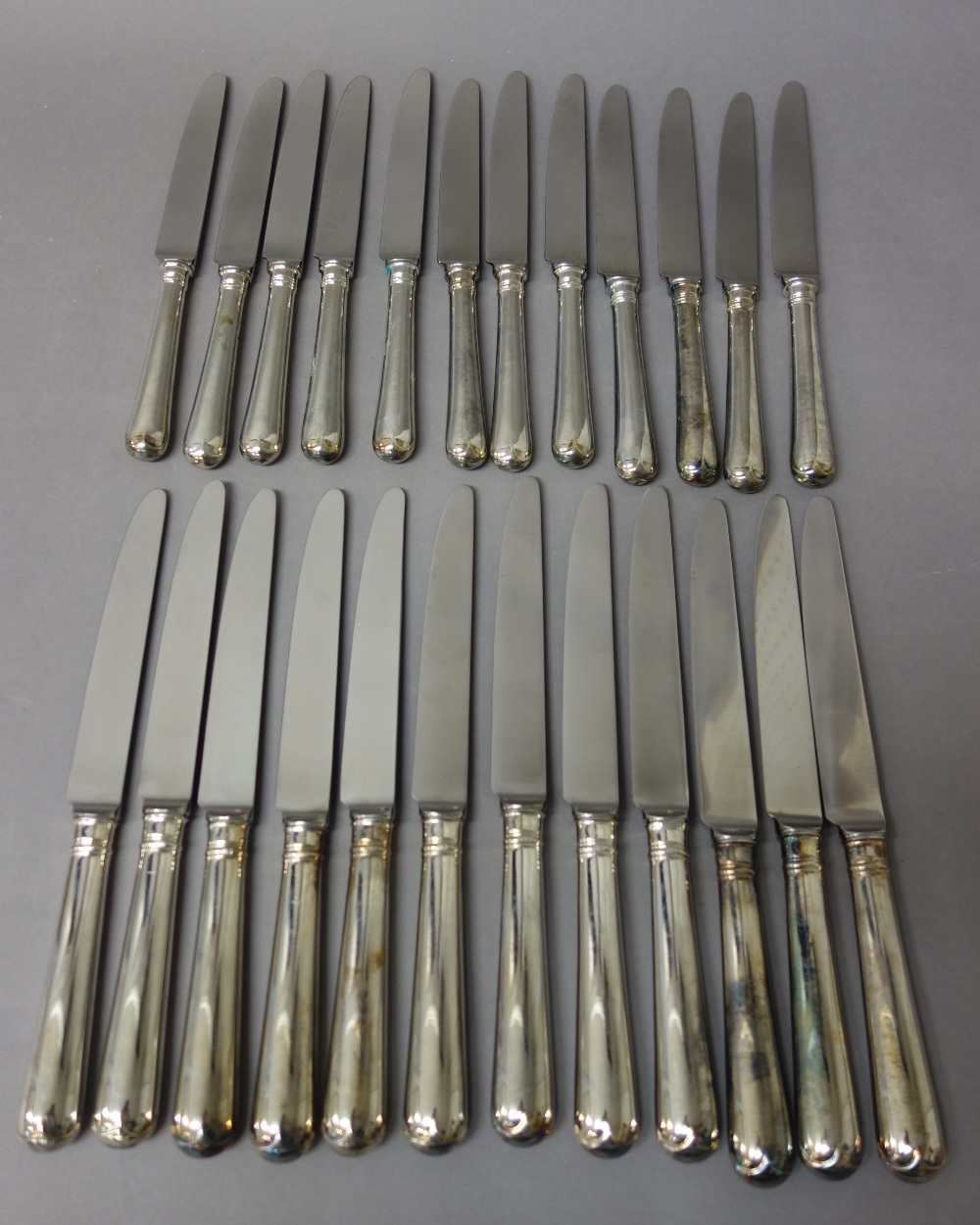 Twelve table knives, having steel blades and with loaded silver handles and twelve cheese knives,