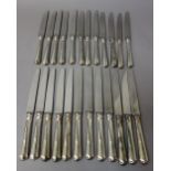 Twelve table knives, having steel blades and with loaded silver handles and twelve cheese knives,