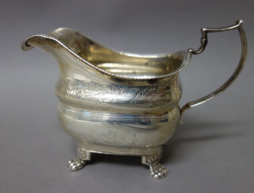 A late George III Irish silver milk jug, having a decorated rim, raised on four paw feet,