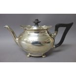 A silver three piece tea set, comprising; a teapot having black fittings,