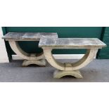 A pair of faux stone console tables, each with rectangular slab tops on open 'U' shaped undertier,