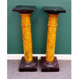 A pair of jardiniere stands, each with ebonised square top over faux marble painted column,