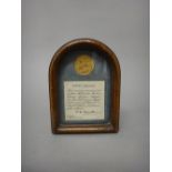 A George V sovereign, 1912, displayed in an arched oak glazed frame, detailed 'EGYPT' SALVAGE,