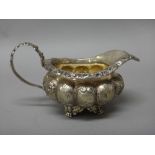 A George IV silver milk jug, of compressed lobed circular form, with embossed decoration,