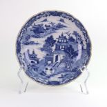 A Chinese Export blue and white dish, painted with a willow pattern water landscape,