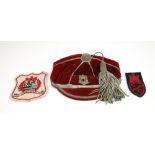 A Naval red velvet and silver braid and tasselled cap and two cloth badges,