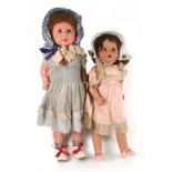 Two composite dolls, both wearing bonnets, one in pink, one in a blue dress, both with closing eyes,