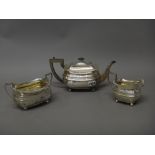 A silver three piece tea set, comprising; a teapot, a twin handled sugar bowl and a milk jug,