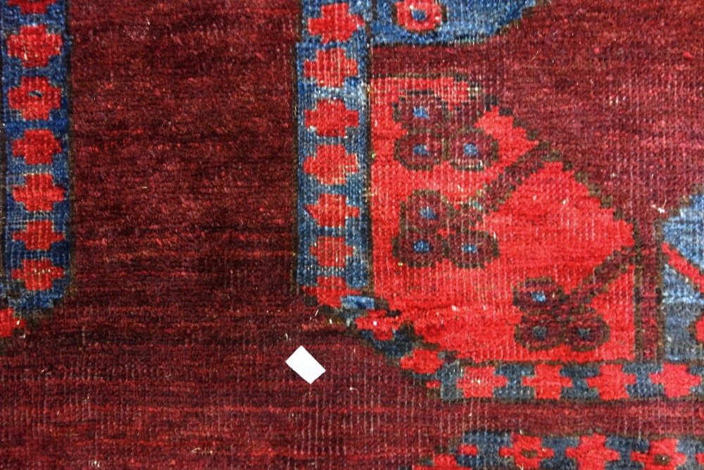 An Afghan Esari carpet, the dark madder field with three columns of six bold guls, - Image 2 of 12