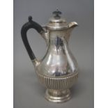 A late Victorian silver hot water jug, of baluster shaped form, with partly fluted decoration,