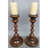 A pair of Continental fruitwood candlesticks, of turned circular form, on dished bases,