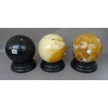 Three hardstone spheres on ebonised wooden stands, 20th century, one smaller,