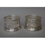 A pair of foreign bottle coasters, each with a scroll pierced border, on a circular base,