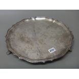 A silver salver, of shaped circular form, having a pie-crust rim, raised on three feet,