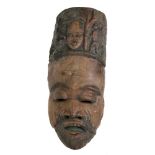 A carved tribal mask, of long proportions, carved with a face, figures,