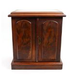 A Victorian walnut cigar cabinet, fitted with three drawers enclosed by a pair of arched doors,