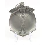 An Art Nouveau pewter dish, of shaped outline, centred by a young lady with flowing hair,