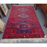 A Caucasian rug of Kazak design, the madder field with three bold indigo medallions,