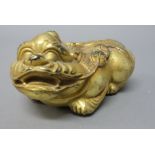 A Chinese gilt-bronze mythical beast, modelled crouching holding a string of cash in its mouth, 9cm.