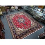 An Heriz carpet, Persian, the madder field with a bold indigo and ivory medallion,