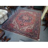 A Heriz carpet, Persian, the madder field with a bold indigo medallion, ivory and madder spandrels,