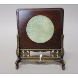 A Chinese jade circular plaque, carved as a chrysanthemum, inset into a wood frame and bronze stand,