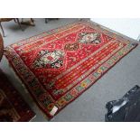 A Persepolis Shiraz rug, Persian, the madder field with three black medallions,