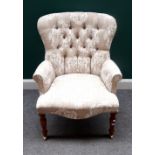 A Victorian style button back easy armchair, on turned stained beech supports,