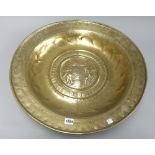 A brass alms dish, 17th century, embossed with two men gathering harvest,