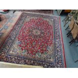 An Esfahan carpet, Persian, the madder field with an ivory and indigo sunburst medallion,