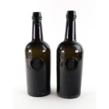 A pair of green glass wine bottles, by H