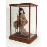 A modern Japanese doll, 27cm high, in glazed wooden case.