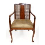 An Art Deco mahogany open arm elbow chair, with cane panel back, upholstered seat, on cabriole legs.