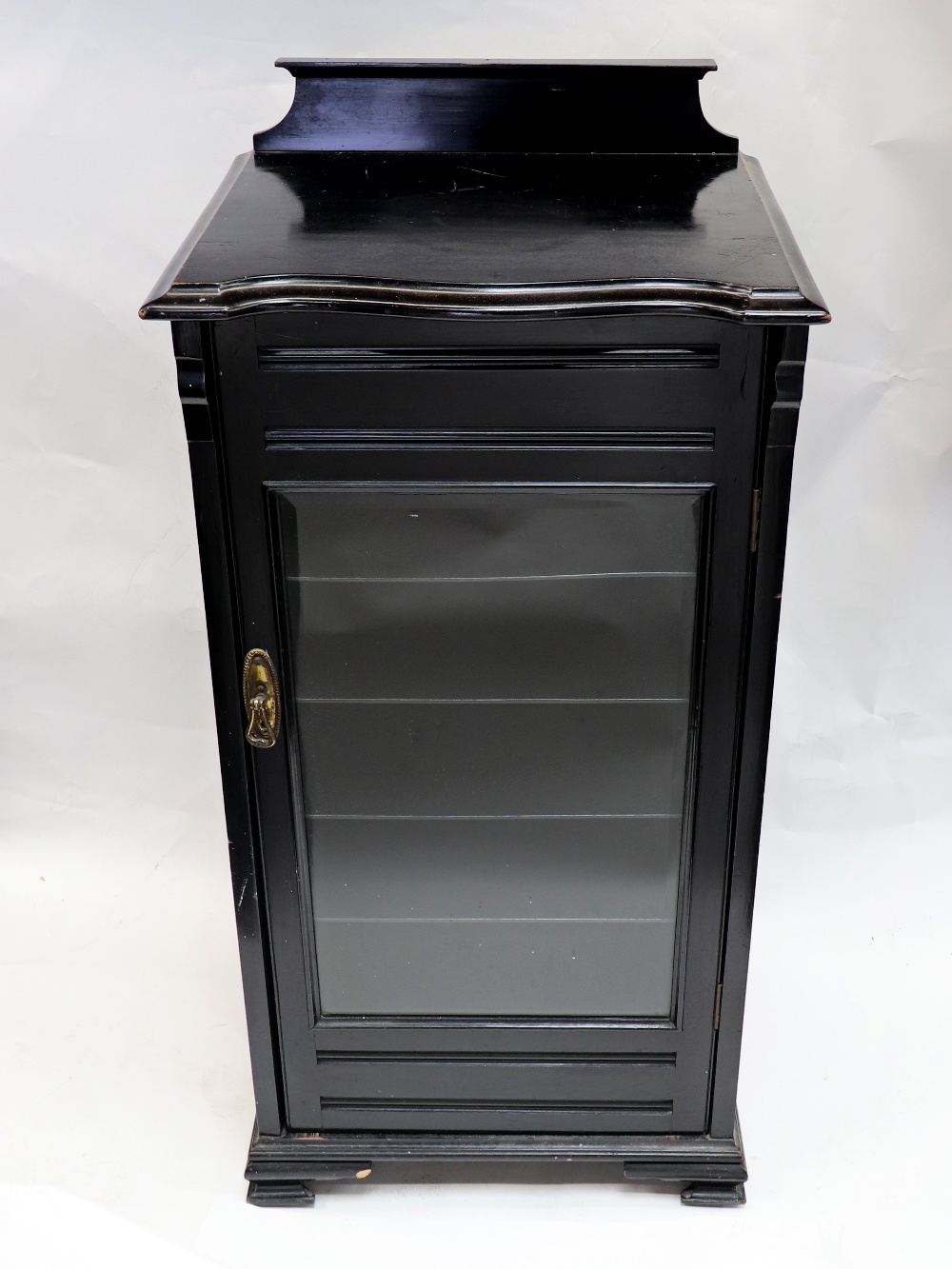 A late Victorian ebonised music cabinet, enclosed by a glazed door,