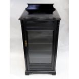 A late Victorian ebonised music cabinet, enclosed by a glazed door,