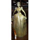An early 20th century brass figural fireguard formed as a woman in Victorian dress,