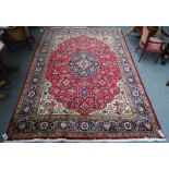 A Tabriz carpet, Persian, the madder field with a lobed dark indigo and ivory medallion,
