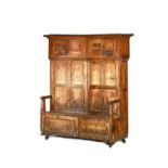 A George III pine, free standing, curved back bacon settle, with opposing panelled cupboards,