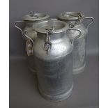 Three vintage French aluminium milk churns, each with twin handles,