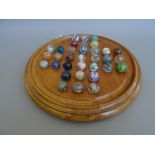 A Victorian fruitwood solitaire board of turned circular form containing 33 marbles.