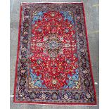 A Kashan carpet, Persian, the madder field with a shaped indigo medallion supported by palmette,