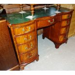 A 20th century mahogany double serpentine writing desk with green leather inset top,