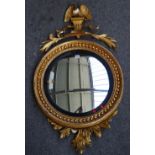 A Regency gilt framed convex wall mirror with eagle surmount and acanthus spray lower frieze,