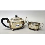 A silver teapot, of rectangular form, with curved corners, raised on four spherical feet,