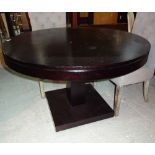 A 20th century ebonised circular dining table, on plinth base, 120cm wide x 80cm high.