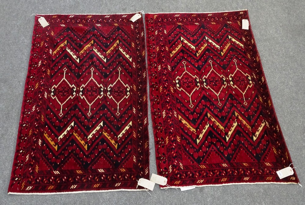 A pair of Uzbeck chuvals, the madder field with three single medallions zig-zag supporting bands,