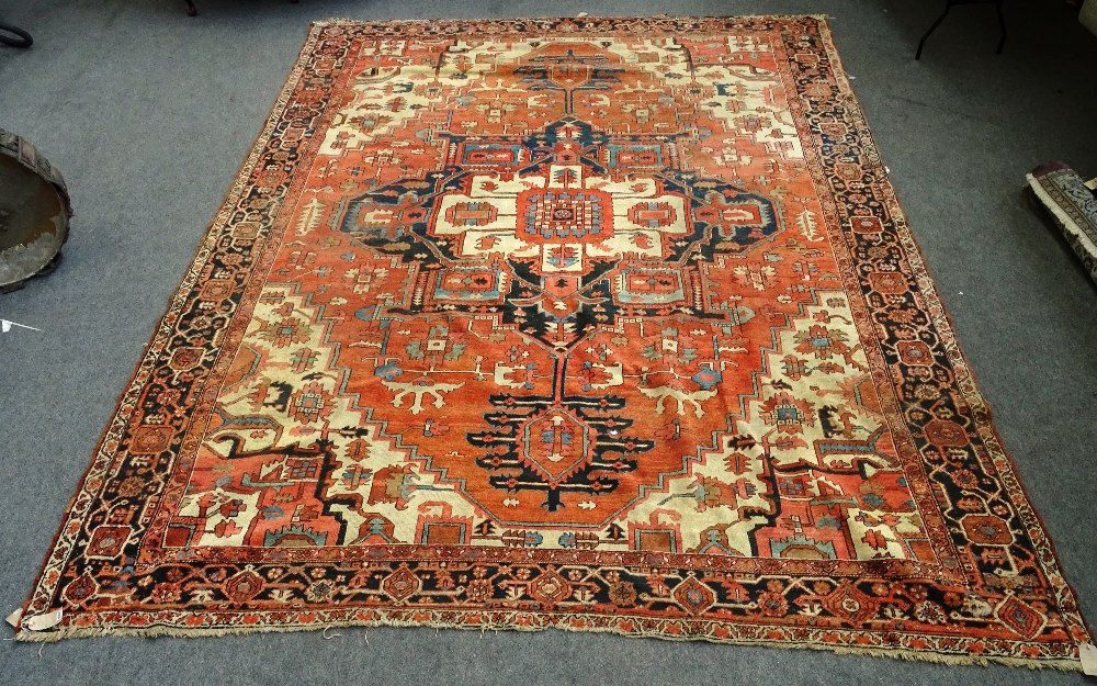 An Heriz carpet, Persian, the madder field with a bold angular pole medallion, ivory spandrels,