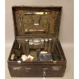 A crocodile travelling toilet case, containing a part set of silver mounted glass bottles and jars,